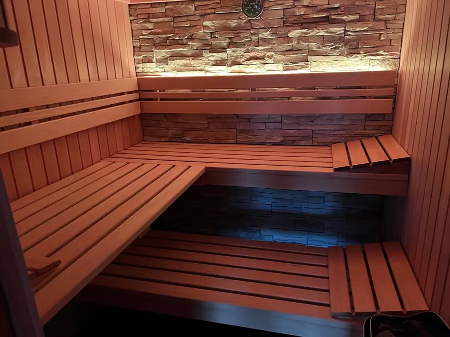 Finnische Sauna mit Holzbänken und Steinwand